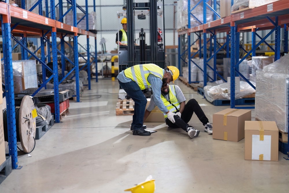 Injured man in warehouse being helped by another employee